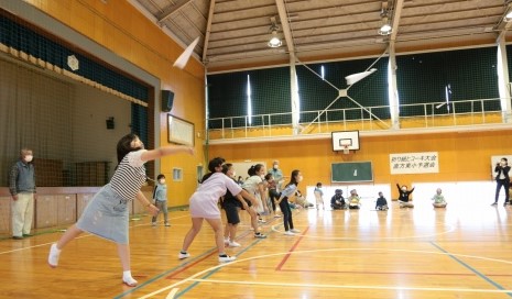 遠くに紙飛行機を飛ばす児童