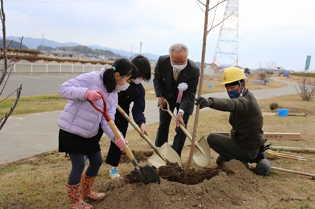 市長と子ども２名で桜の木の植樹をしている写真