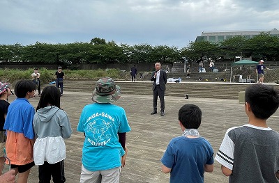市長が河川敷でカヌースクール参加者の前で話をしている写真