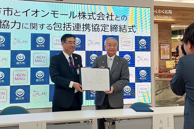 協定書を掲げる直方市長とイオンモール株式会社の首藤部長