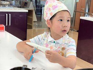 キッチンペーパーをはさみでカットして落し蓋を作るお子さん