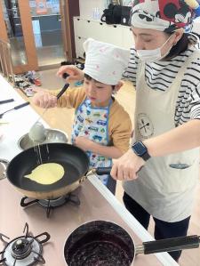 フライパンにクレープ生地を流し入れる親子