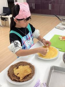 クレープの上に具材を並べる女の子