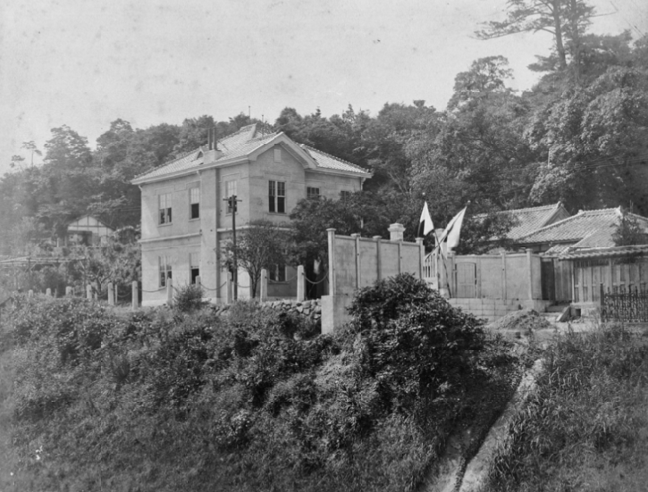 二階建ての木造洋風建築　門に交差する二本の日の丸