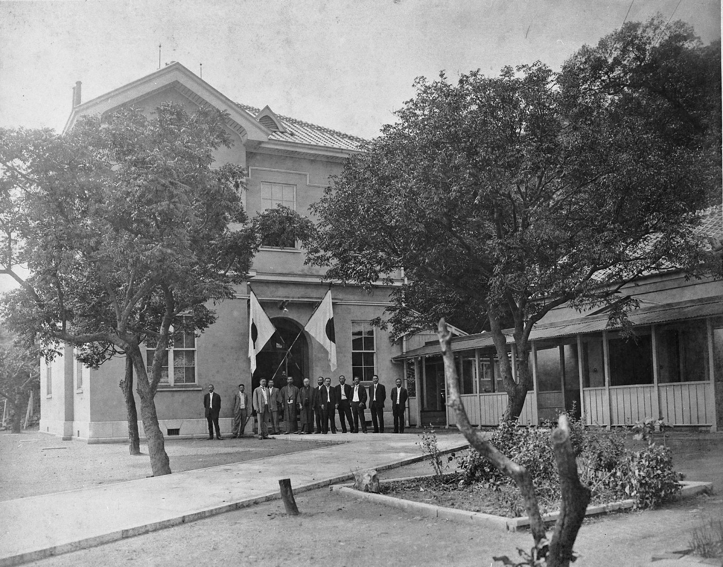 二階建ての木造洋風建築の前に集う人々